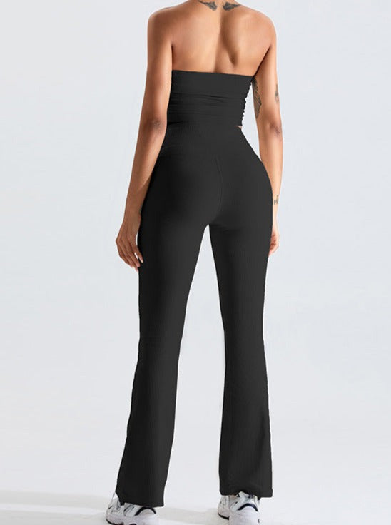 Woman wearing a black strapless jumpsuit with flared pants, showcasing a back view. Fashionable outfit for casual or evening wear.