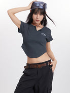 Young woman in a stylish dark crop top and cargo pants, wearing a headscarf and hoop earrings, striking a confident pose. Fashionable streetwear outfit.