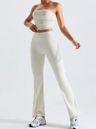 Woman in white ribbed two-piece outfit with strapless top and flared pants, wearing white sneakers. Fashionable casual wear for women.