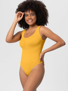 Woman in yellow sleeveless bodysuit smiling, showcasing casual fashion. Perfect for summer style, comfortable fit, and trendy wardrobe essentials.
