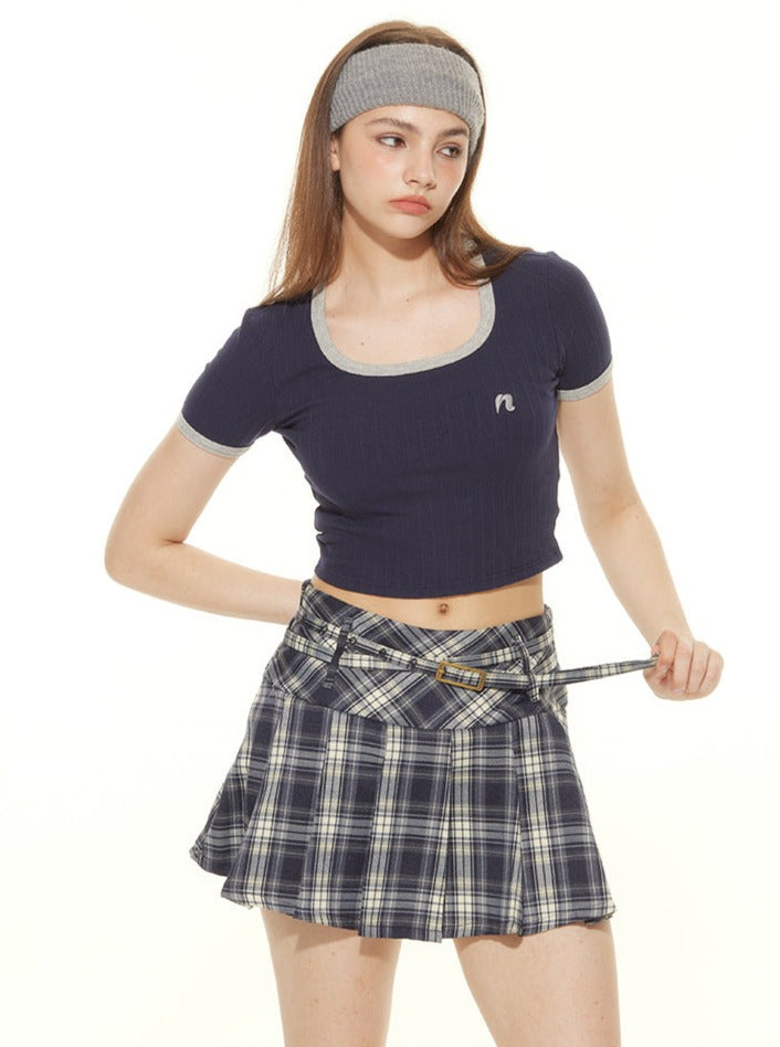 Young woman in a navy crop top and plaid skirt, wearing a gray headband. Fashionable casual outfit, trendy teen style, plaid skirt fashion.