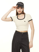 Woman in a stylish black and white outfit, wearing a cap and choker. Fashionable crop top and high-waisted pants. Trendy streetwear look.