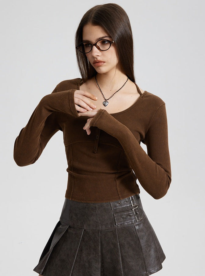 Woman in brown long-sleeve top and black pleated skirt, wearing glasses and a necklace. Fashionable casual outfit, modern style.