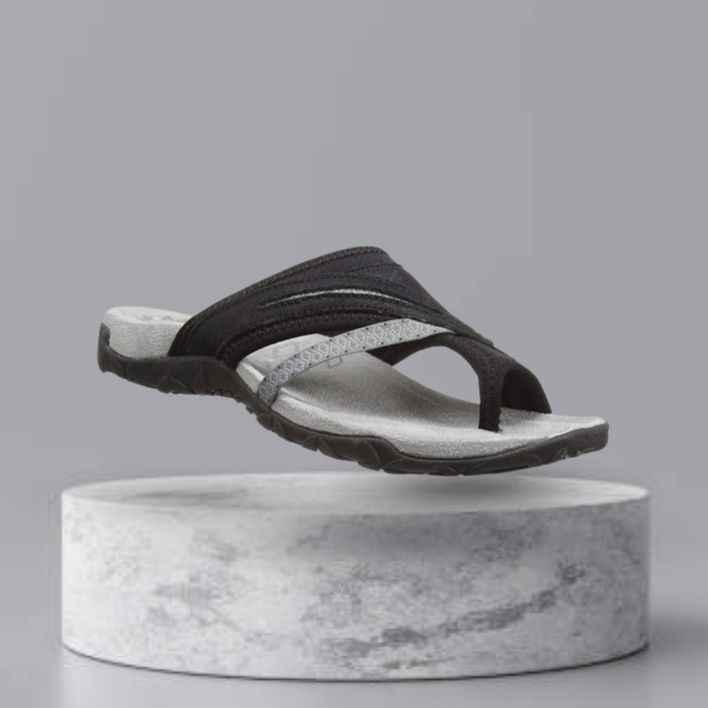 Black and gray ergonomic flip-flop sandal with textured sole, displayed on a minimalist gray pedestal. Ideal for casual summer wear and comfort.