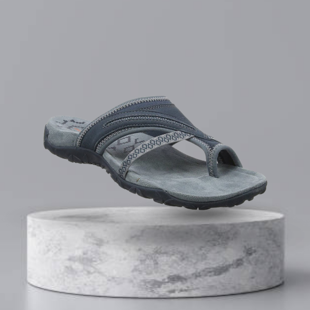 Gray men's sandal with textured sole and geometric strap design, displayed on a marble pedestal. Ideal for casual wear. Comfortable and stylish footwear.