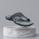 Gray men's sandal with textured sole and geometric strap design, displayed on a marble pedestal. Ideal for casual wear. Comfortable and stylish footwear.