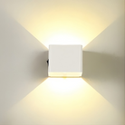 Modern white wall sconce with cube design, emitting warm LED light in an upward and downward pattern. Ideal for contemporary home lighting decor.