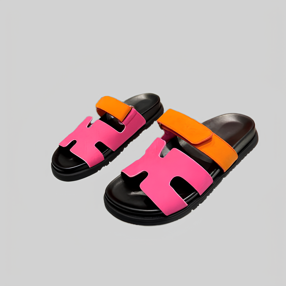 Colorful sandals with pink and orange straps on a gray background, featuring a modern design and black soles. Fashionable summer footwear.