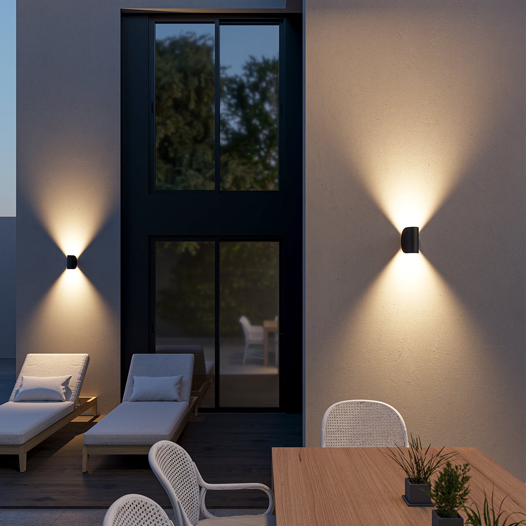 Modern outdoor patio with sleek wall lights, wooden lounge chairs, and a dining table, creating a cozy evening ambiance. Ideal for contemporary home design.