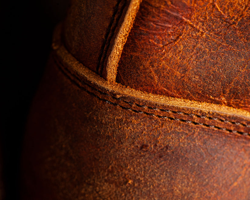 Close-up of brown leather with detailed stitching, showcasing high-quality craftsmanship and texture. Perfect for luxury leather goods and fashion keywords.