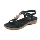 Black women's sandal with rhinestone embellishments, cushioned sole, and elastic ankle strap. Stylish summer footwear, comfortable and trendy design.