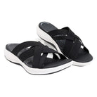 Black slip-on sandals with crisscross straps and cushioned white soles, ideal for casual wear. Comfortable women's footwear, perfect for summer.