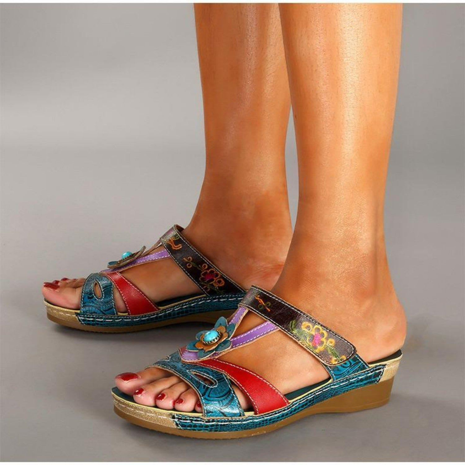 Colorful women's wedge sandals with floral embroidery, featuring blue, red, and purple leather straps. Stylish summer footwear for casual wear.