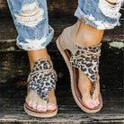 Women's leopard print sandals with open toes and ankle support, paired with ripped jeans. Stylish summer footwear for casual outings.