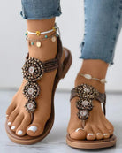 Beaded boho sandals on feet with anklets, featuring intricate floral designs, paired with distressed jeans. Perfect for summer fashion and casual wear.