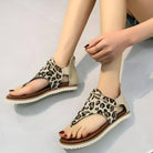 Leopard print women's sandals with open toe design, flat sole, and ankle strap. Stylish summer footwear, perfect for casual outings and beachwear.