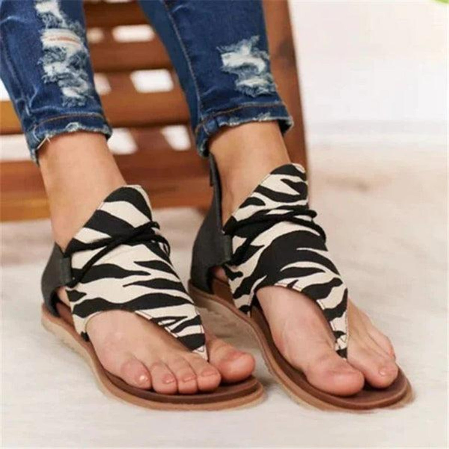 Zebra print sandals with open-toe design and lace-up detail, paired with ripped jeans. Stylish women's footwear for casual summer fashion.