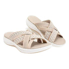 Beige women's slip-on sandals with crisscross straps and chevron pattern, featuring cushioned soles. Perfect for casual summer wear.