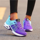 Purple and blue athletic running shoes with breathable mesh design, worn by a person on a street. Stylish, comfortable sneakers for sports and casual wear.