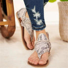 Woman wearing stylish snake print sandals with distressed denim jeans, showcasing trendy summer footwear fashion.