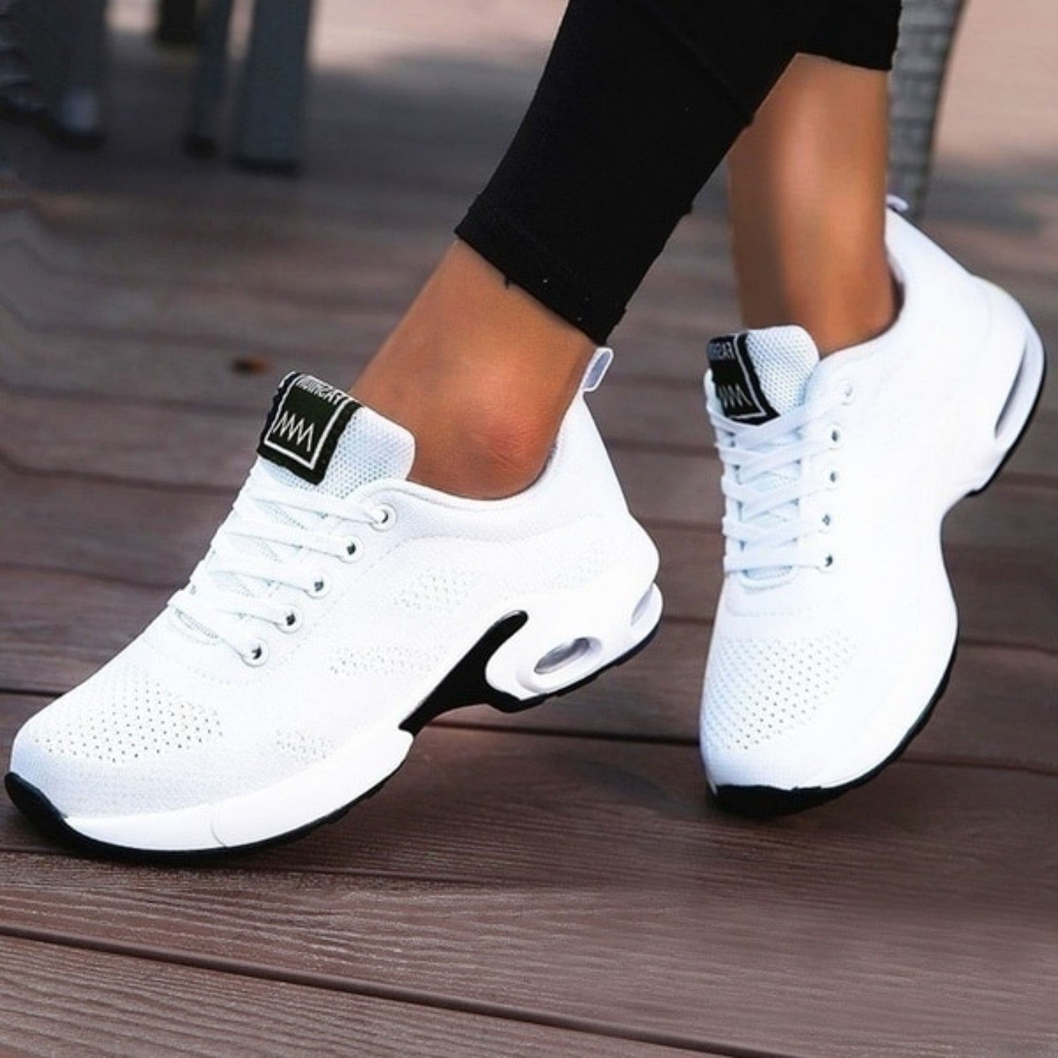 White athletic sneakers with breathable mesh design, cushioned sole, and black accents, perfect for running and casual wear. Fashionable sports shoes.