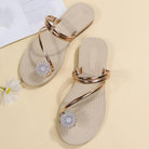 Beige flat sandals with gold straps and floral rhinestone accents on a light background, perfect for summer fashion and casual wear.