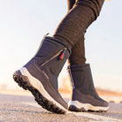 Person wearing black winter boots with rugged soles, walking on pavement. Stylish, durable footwear for cold weather. Ideal for outdoor activities.