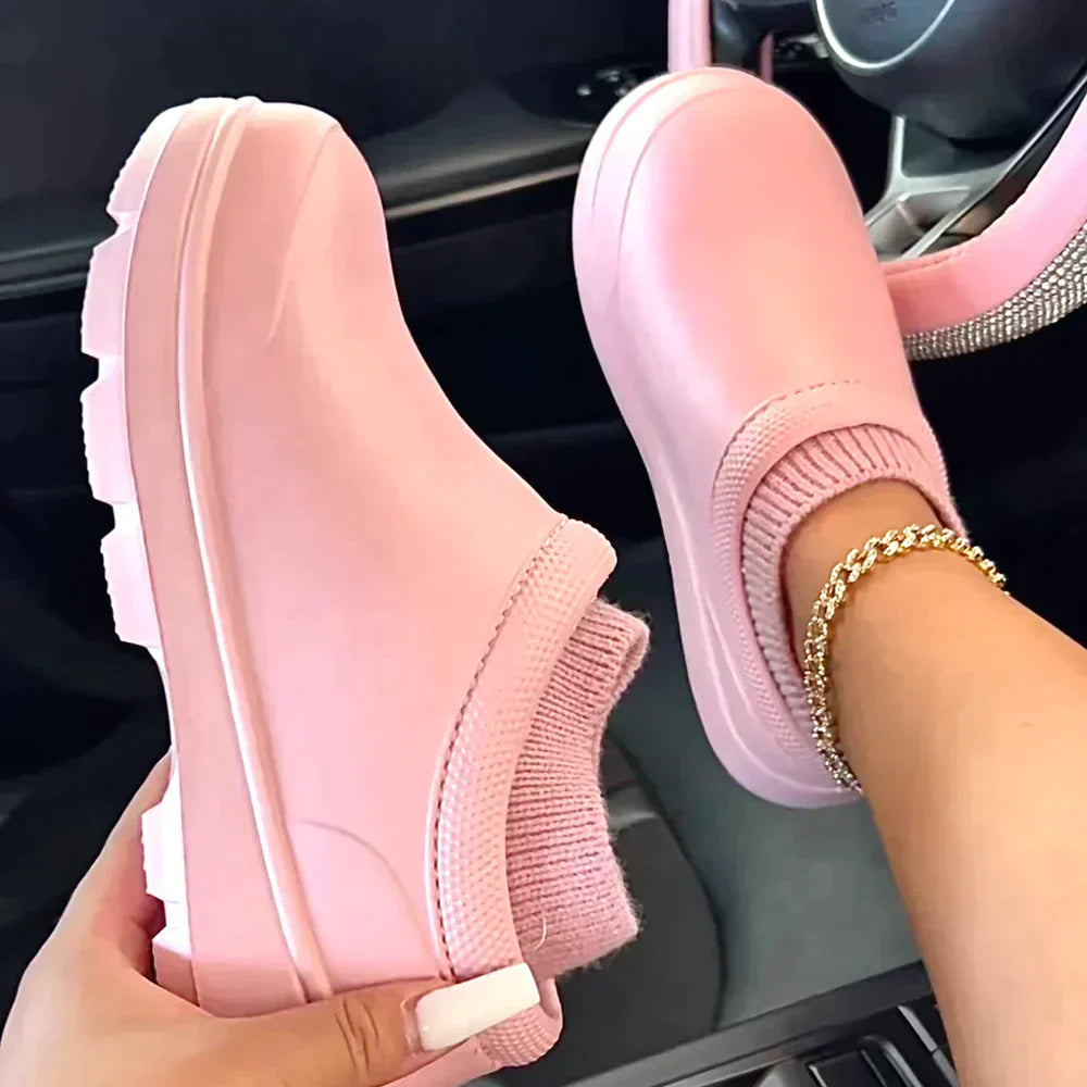 Pink slip-on clogs with thick soles and knit socks, worn by a person in a car. Trendy footwear, casual style, comfortable shoes for women.