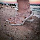 Comfortable pink sandals on sandy beach at sunset, featuring durable straps and cushioned soles. Perfect for summer travel and outdoor adventures.