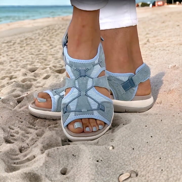 Light blue women's sandals on a sandy beach, featuring adjustable straps and cushioned soles. Perfect for summer fashion and comfortable beachwear.