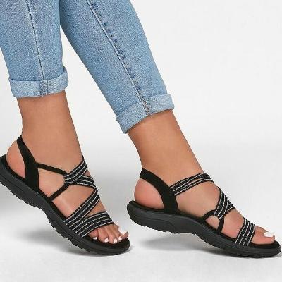 Plus size women's summer sandals with soft sole, black strappy design, casual flat beach shoes, paired with blue jeans, 2022 fashion trend.