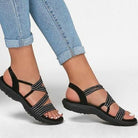 Plus size women's black strappy sandals with soft sole, casual summer footwear, paired with blue jeans, ideal for beach and everyday wear.