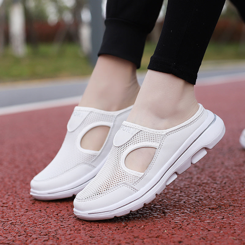 White breathable mesh slip-on walking shoes with cushioned soles on a red track. Comfortable, lightweight footwear for outdoor activities.