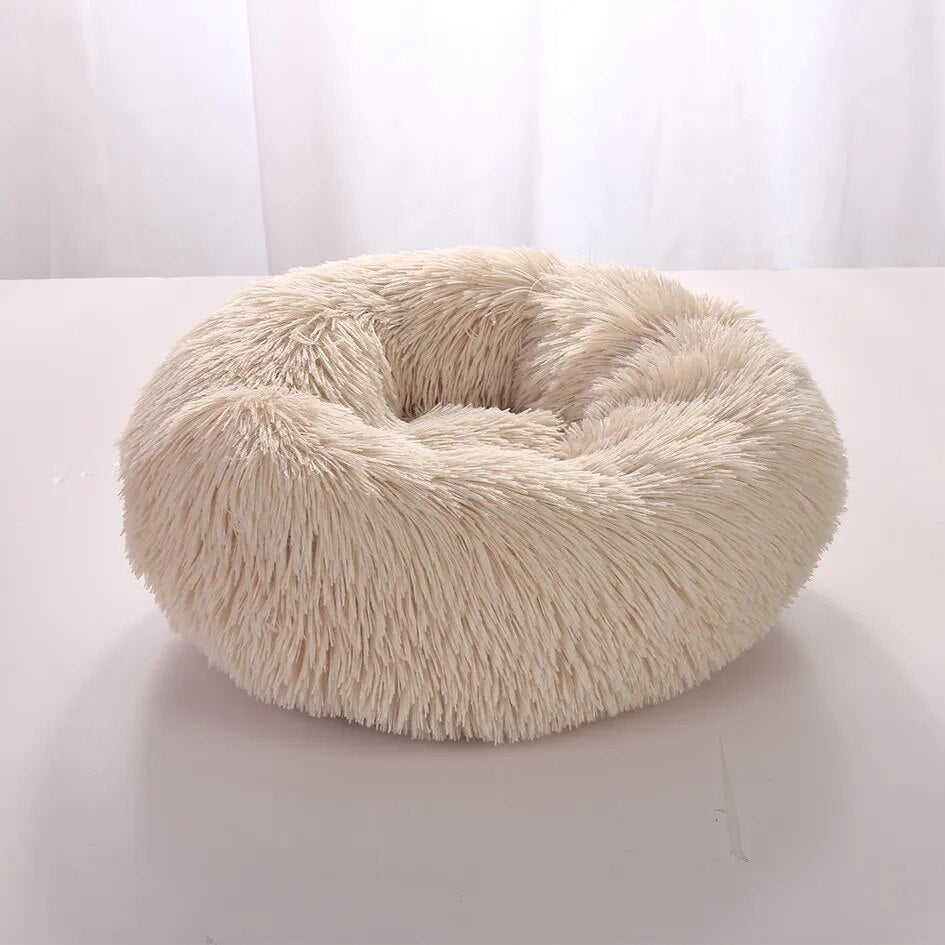 Fluffy beige round pet bed with soft faux fur texture, ideal for cats and small dogs, providing comfort and warmth. Perfect for cozy pet lounging.