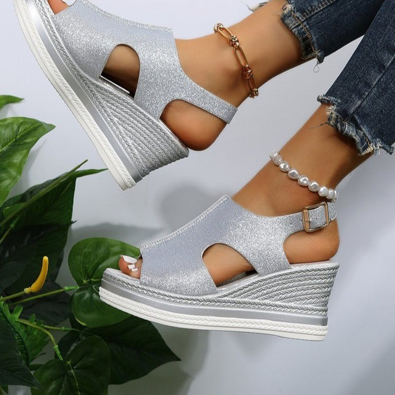 Silver wedge sandals with open-toe design, ankle strap, and textured platform. Perfect for summer fashion and casual wear. Stylish women's footwear.