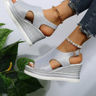 Silver wedge sandals with open toe and ankle strap, paired with pearl anklet and jeans. Fashionable women's footwear, summer style.