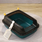 Green and black covered cat litter box with scoop on rug, pet cleaning accessory.
