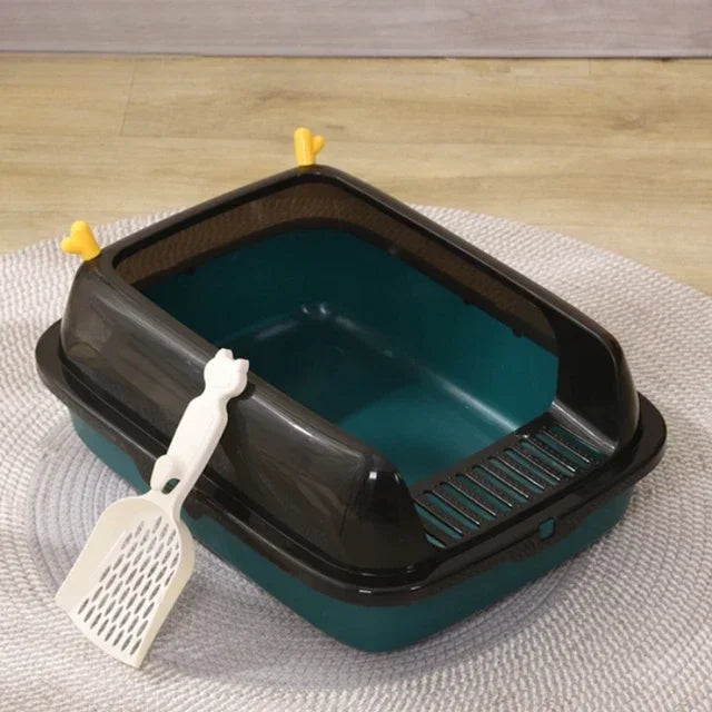 Green and black covered cat litter box with scoop on rug, pet cleaning accessory.