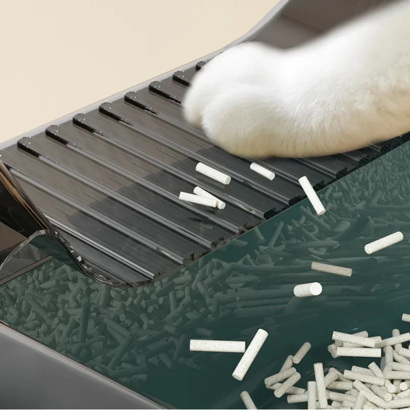 Cat paw on litter box ramp with scattered white litter pellets, anti-tracking design.