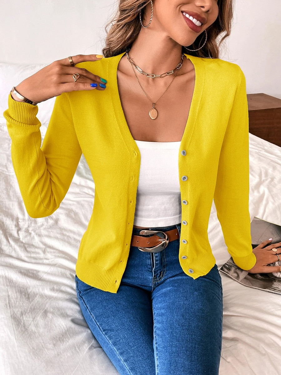 Woman wearing yellow button-up cardigan, white top, blue jeans; casual fashion outfit.