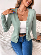 Woman wearing mint green cardigan, white top, blue jeans; casual fashion outfit.