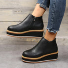 Black platform ankle boots with side zipper, paired with frayed hem jeans. Stylish women's footwear, casual fashion, elevated sole design.