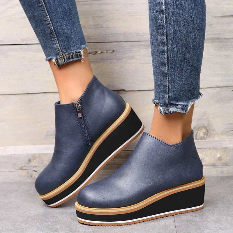 Women's blue platform wedge ankle boots with side zipper, paired with distressed skinny jeans. Fashionable footwear for casual and trendy outfits.