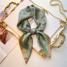 Elegant green paisley silk scarf on a decorative tray, perfect for fashion accessories. Enhance your style with this luxurious, versatile neckwear.