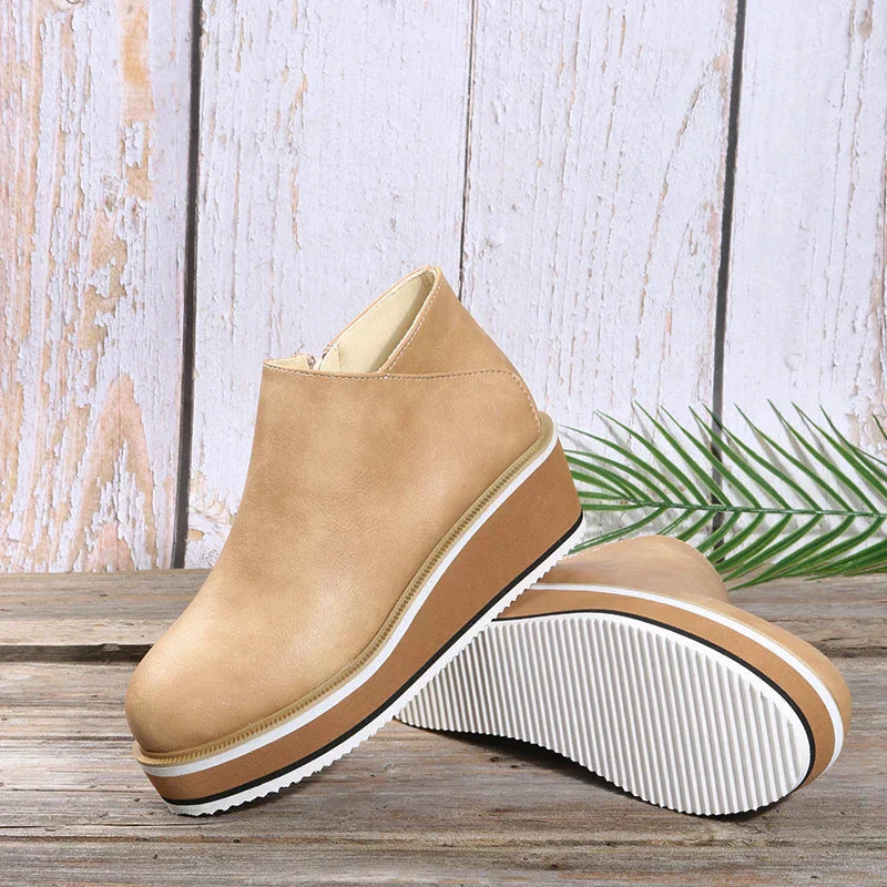 Beige platform wedge ankle boots with white ribbed soles on wooden background, stylish women's footwear, casual fashion shoes, side and bottom view.