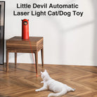 Little Devil Automatic Laser Light Cat/Dog Toy on wooden table, projecting red laser dot on floor, engaging white cat. Interactive pet toy.