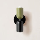 Modern wall sconce with green and black cylindrical design, minimalist lighting fixture, contemporary home decor, energy-efficient LED bulb.