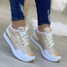 Stylish gold and white women's sneakers with quilted design, white laces, and gold accents, paired with ripped jeans. Fashionable casual footwear.