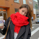 Woman in stylish black coat and vibrant red scarf holding a coffee cup on urban street. Fashionable winter outfit, city background, casual look.