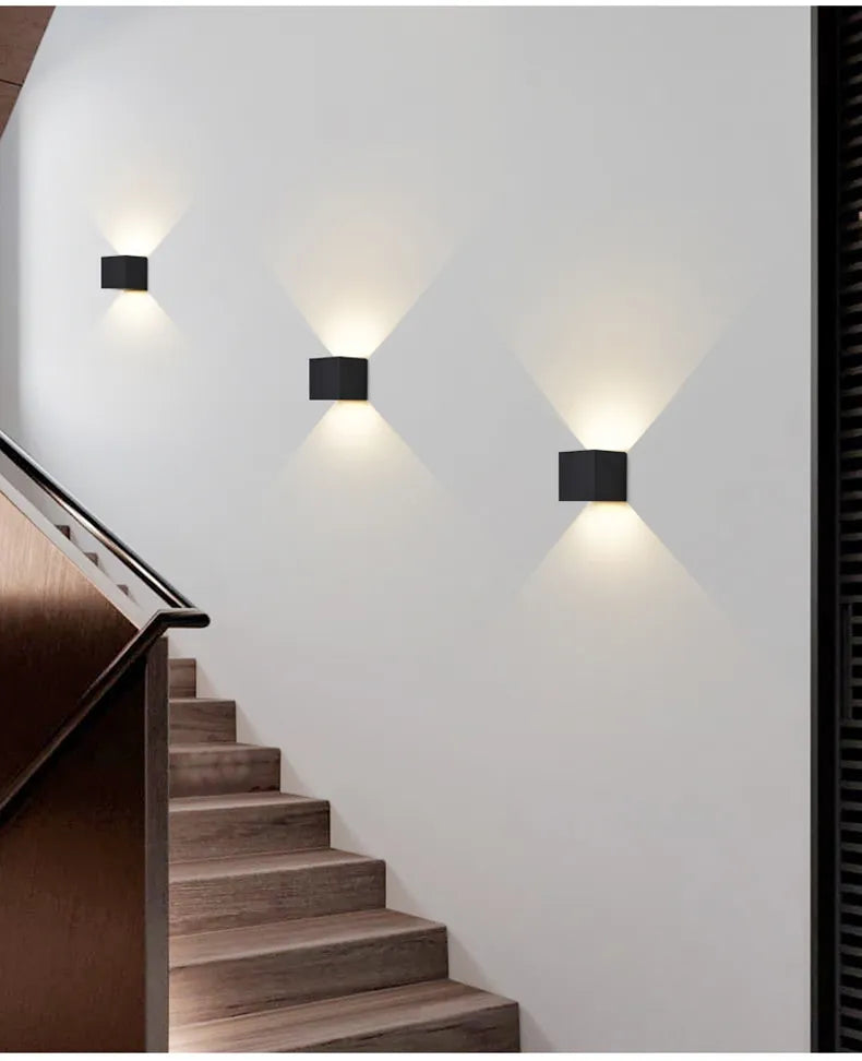 Modern black wall sconces illuminate a minimalist staircase with wooden steps, creating a stylish and contemporary home interior lighting design.